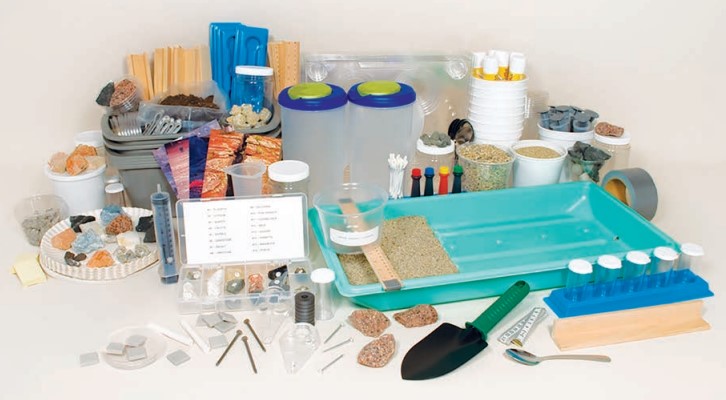 image displaying the items in an equipment kit laid out on a table, including rocks, beakers, shovels, and more